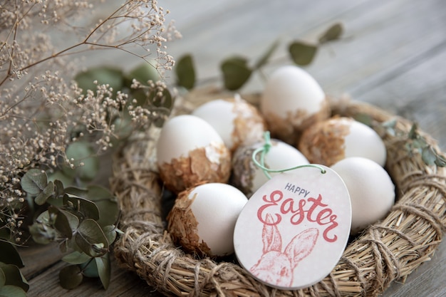 Bodegón de Pascua con huevos de Pascua decorados y nido decorativo sobre una superficie de madera con ramitas secas