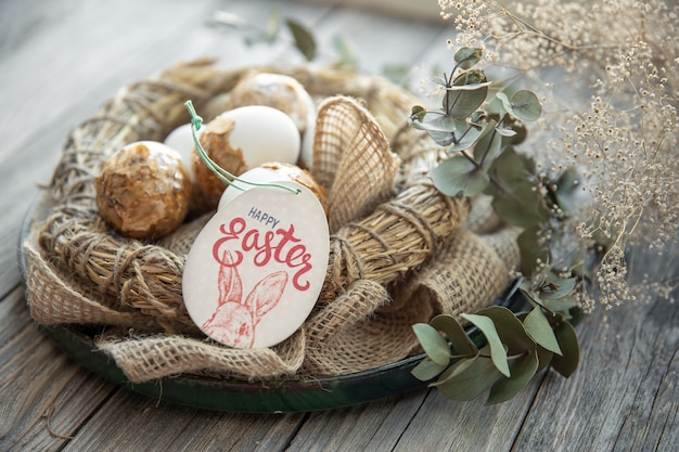 Foto gratuita bodegón de pascua con huevos de pascua decorados y nido decorativo sobre una superficie de madera