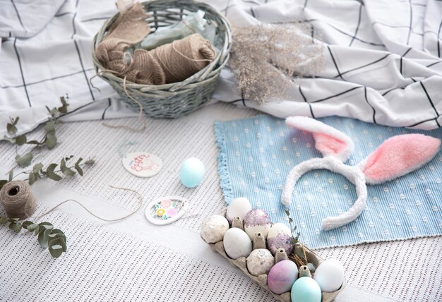 Bodegón de Pascua con orejas de conejo de Pascua decorativas, una bandeja de huevos festivos y elementos decorativos