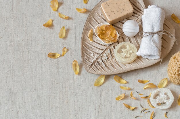 Bodegón de spa con accesorios de baño para el cuidado del cuerpo entre pétalos de flores vista superior. Concepto de salud e higiene.