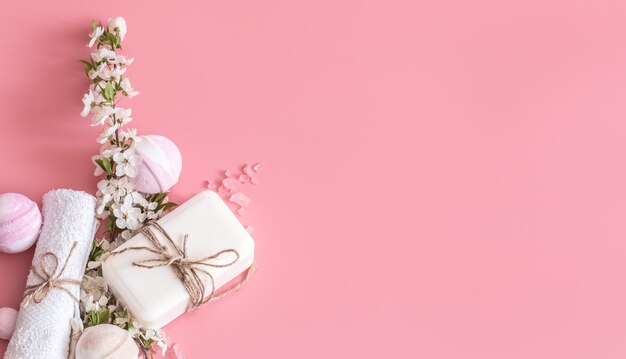Bodegón de spa en pared rosa con flores de primavera