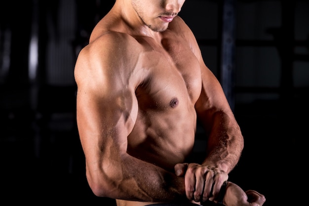Bodybuilder joven con los brazos musculares