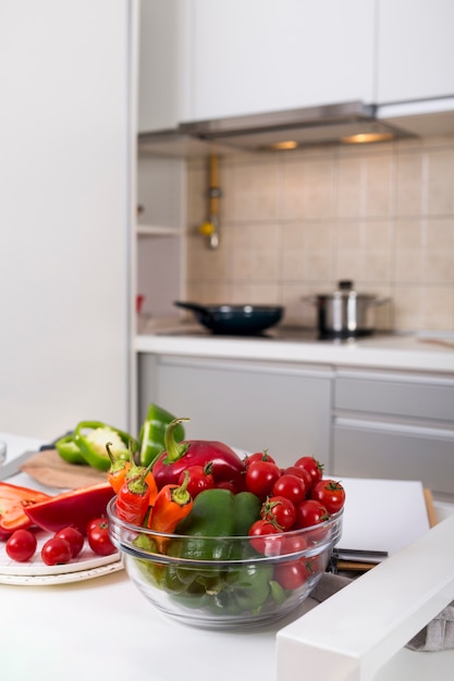 Foto gratuita bol de cristal con ají; pimiento y tomates cherry en la mesa en la cocina