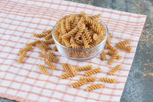 Un bol de vidrio de pasta fusilli, sobre la superficie de mármol.