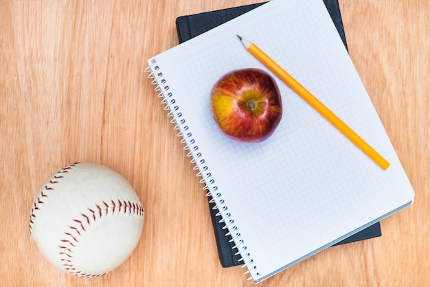 Bola de béisbol cerca de suministros de manzana y escuela