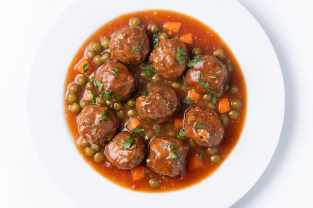 Bola de carne, guisantes verdes y zanahoria con salsa de tomate aislada sobre un fondo blanco