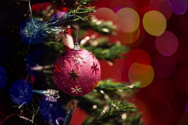 Bola de navidad en el árbol con bokeh sobre fondo rojo