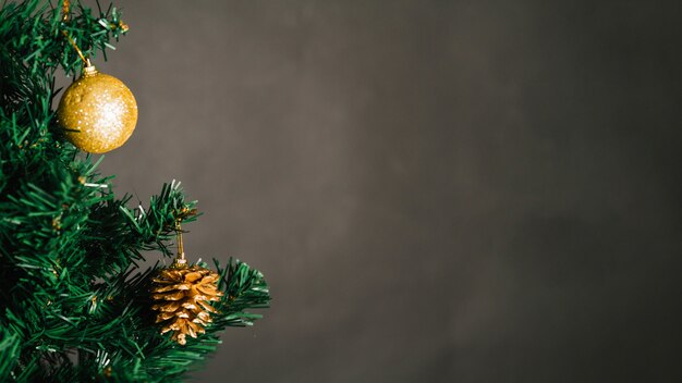 Bola de navidad dorada y pino de piña en árbol