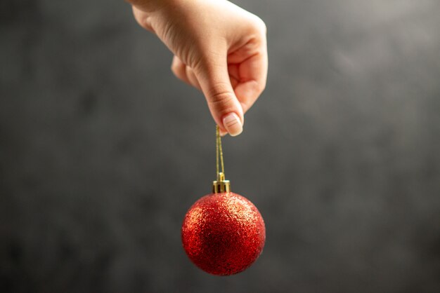 Bola de Navidad vista frontal en mano femenina en el espacio libre oscuro