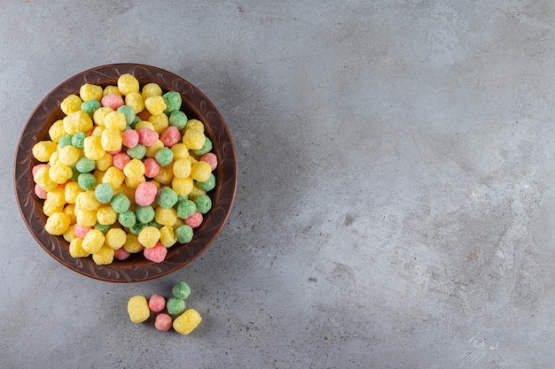 Bolas de cereales de colores colocados en un plato marrón.