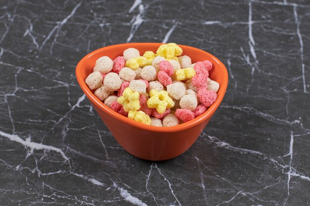 Bolas de cereales de colores en tazón de fuente naranja.