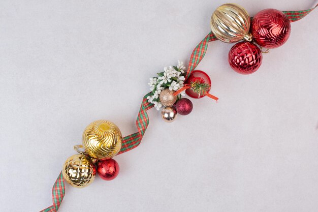 Bolas de decoración navideña con banda en mesa blanca.