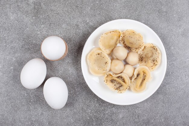 Bolas de masa hervida y huevos en la placa blanca.