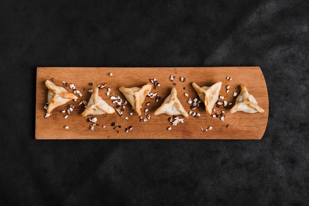 Foto gratuita bolas de masa hervida triangulares en bandeja de madera sobre el fondo negro