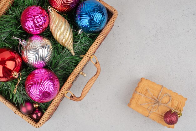 Bolas de Navidad coloridas en canasta con galletas en cuerda.