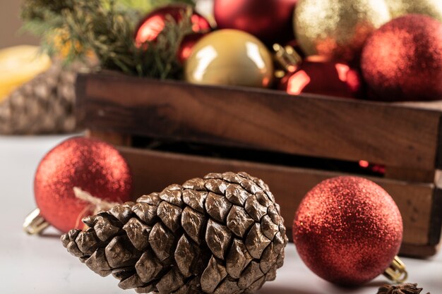 Bolas de Navidad y conos en la caja de madera y sobre la mesa.