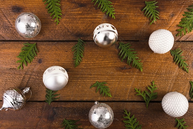 Bolas de Navidad y ramitas de coníferas en tablero de madera