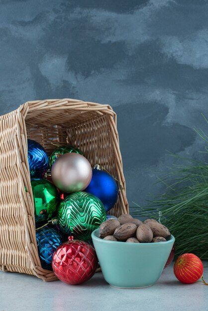 Bolas navideñas con un plato azul de frutos secos. Foto de alta calidad