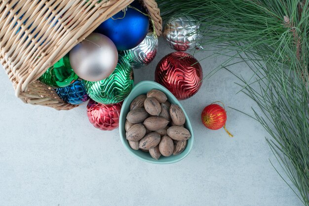 Bolas navideñas con un plato azul de frutos secos. Foto de alta calidad