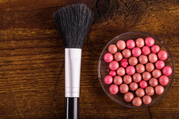 Foto gratuita bolas de polvo y pincel de maquillaje sobre fondo de madera
