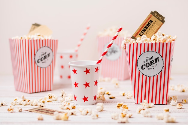 Boleto de cine en la caja de palomitas de maíz con vaso para beber y paja en mesa de madera