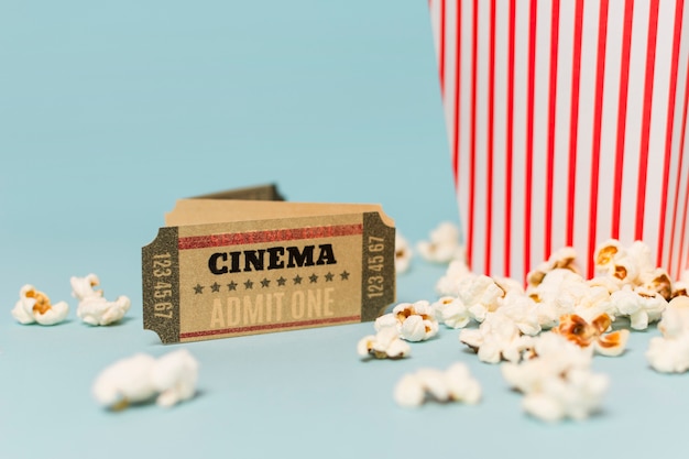 Boleto de cine cerca de las palomitas sobre fondo azul.