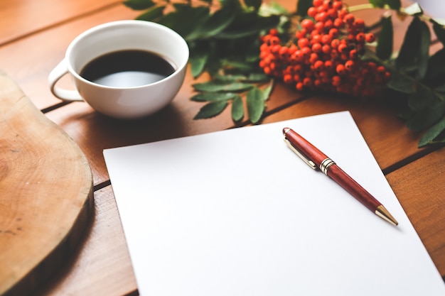 Bolígrafo sobre una hoja de papel con una taza de café de fondo