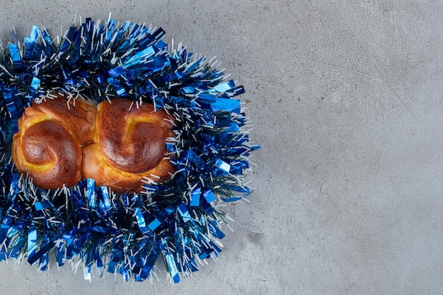 Bollo dulce envuelto con guirnalda azul sobre mármol