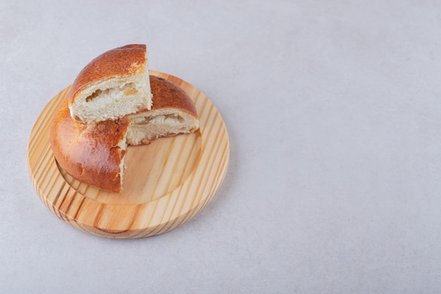 Bollo dulce en rodajas sobre placa de madera, sobre el mármol.