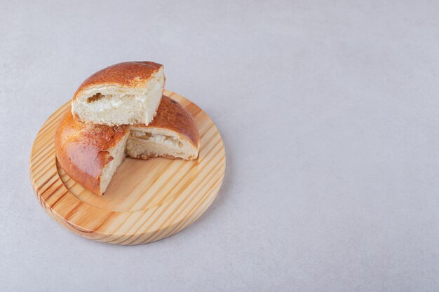 Bollo dulce en rodajas sobre placa de madera sobre mesa de mármol.