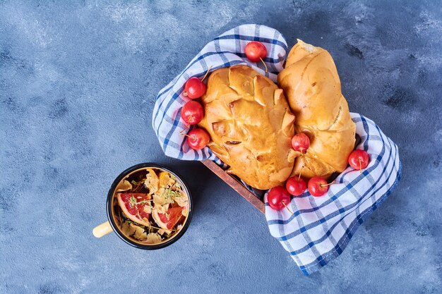 Bollo dulce con té de hierbas sobre una tabla de madera en azul