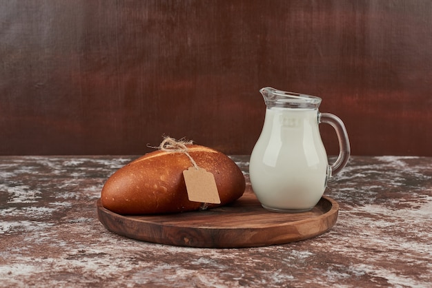 Bollo de pan en mármol con etiqueta y un tarro de leche.