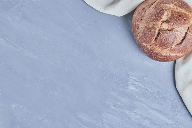 Bollo de pan redondo hecho a mano en la mesa azul.