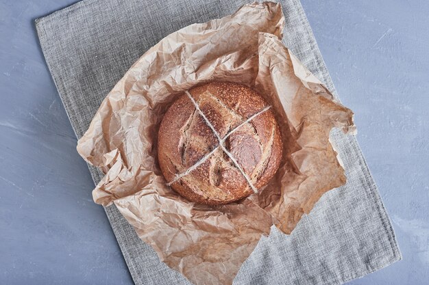 Bollo de pan redondo hecho a mano en la toalla de cocina.