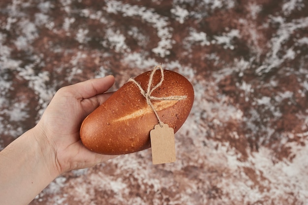 Bollo de pan sobre mármol en la mano.