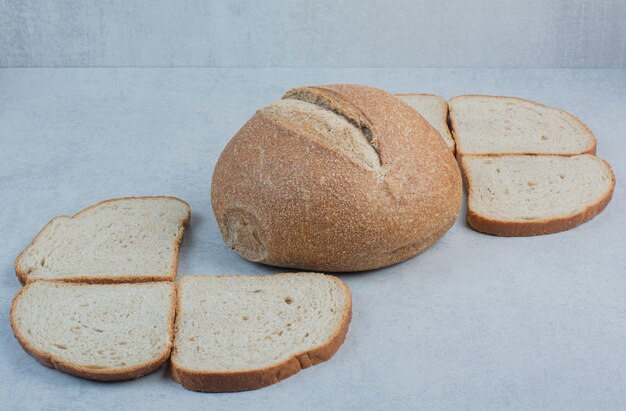 Bollo y rebanadas de pan de centeno sobre fondo de mármol. Foto de alta calidad