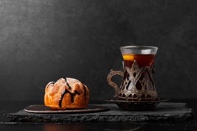 Un bollo de repostería con un vaso de té.