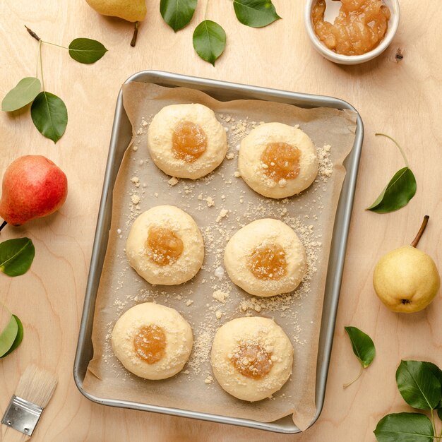 Bollos caseros crudos hechos de masa de levadura con mermelada y peras frescas Mini tartas Receta de cocina sobre un fondo de madera