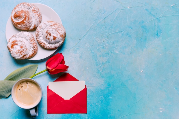 Bollos dulces en un plato con tulipán rojo