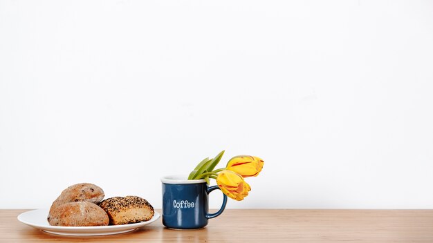 Bollos frescos y taza de café con tulipanes