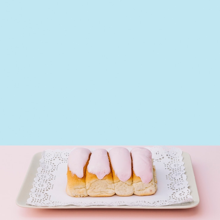 Foto gratuito bollos o dedos cubiertos de hielo sobre la bandeja sobre fondo azul
