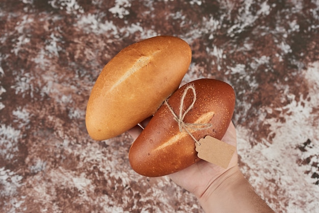 Bollos de pan aislados en mármol en la mano.