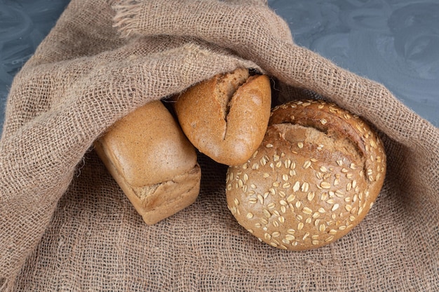 Bollos de pan debajo de una cubierta de tela sobre una mesa de mármol.