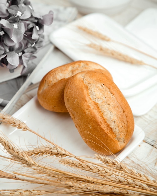 Bollos de pan con rama de trigo sobre la mesa