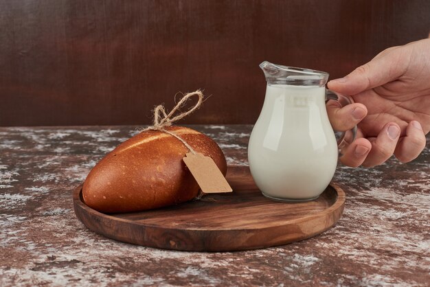 Bollos de pan sobre mármol con un tarro de leche.