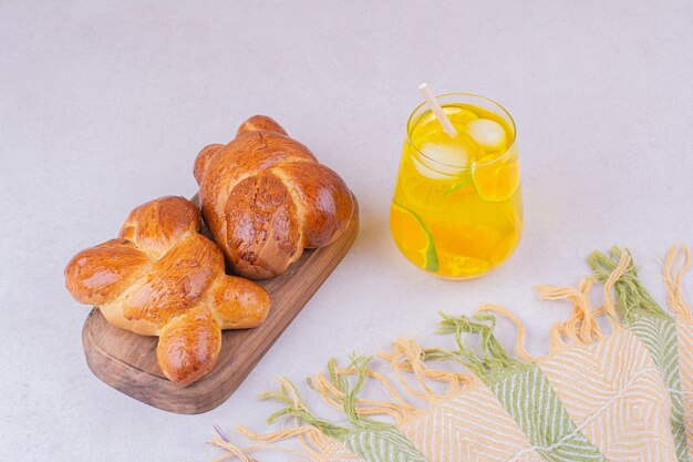 Bollos de pastelería dulce en bandeja de madera con un vaso de limonada.