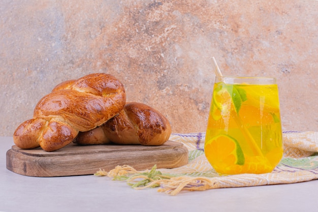 Bollos de pastelería sobre una tabla de madera con un vaso de limonada