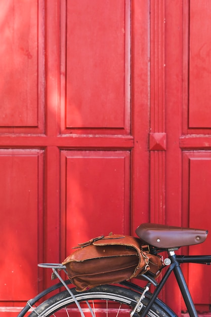 Bolsa de cuero en bicicleta contra puerta roja.