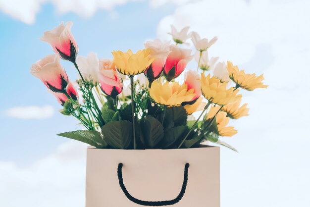 Bolsa con flores de primavera y cielo soleado de fondo.