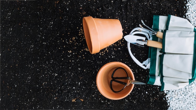 Foto gratuita bolsa con herramientas de jardinería cerca de macetas